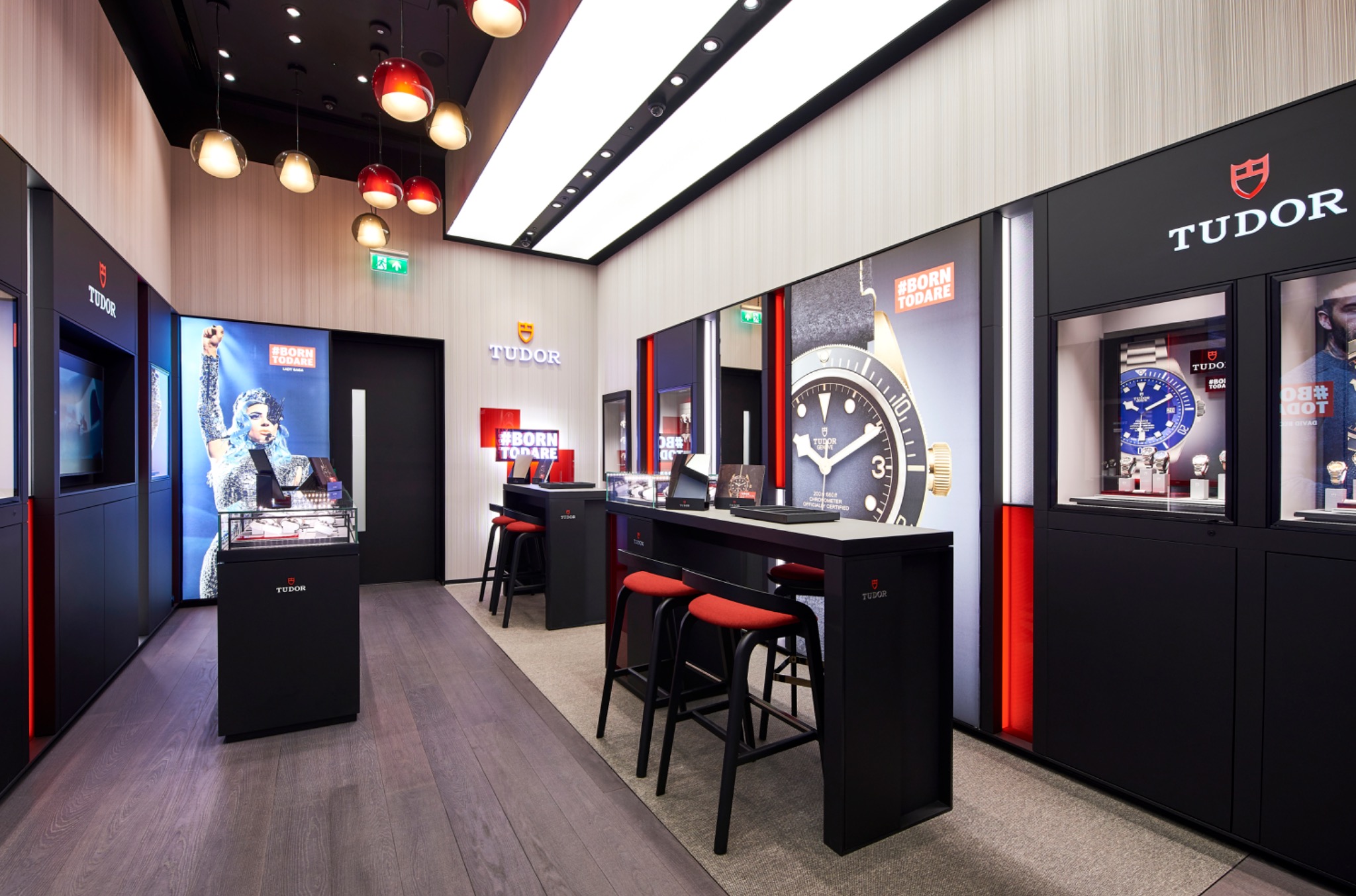 View through the Tudor boutique, with dark display cabinetry, red accents and illuminated watch counters