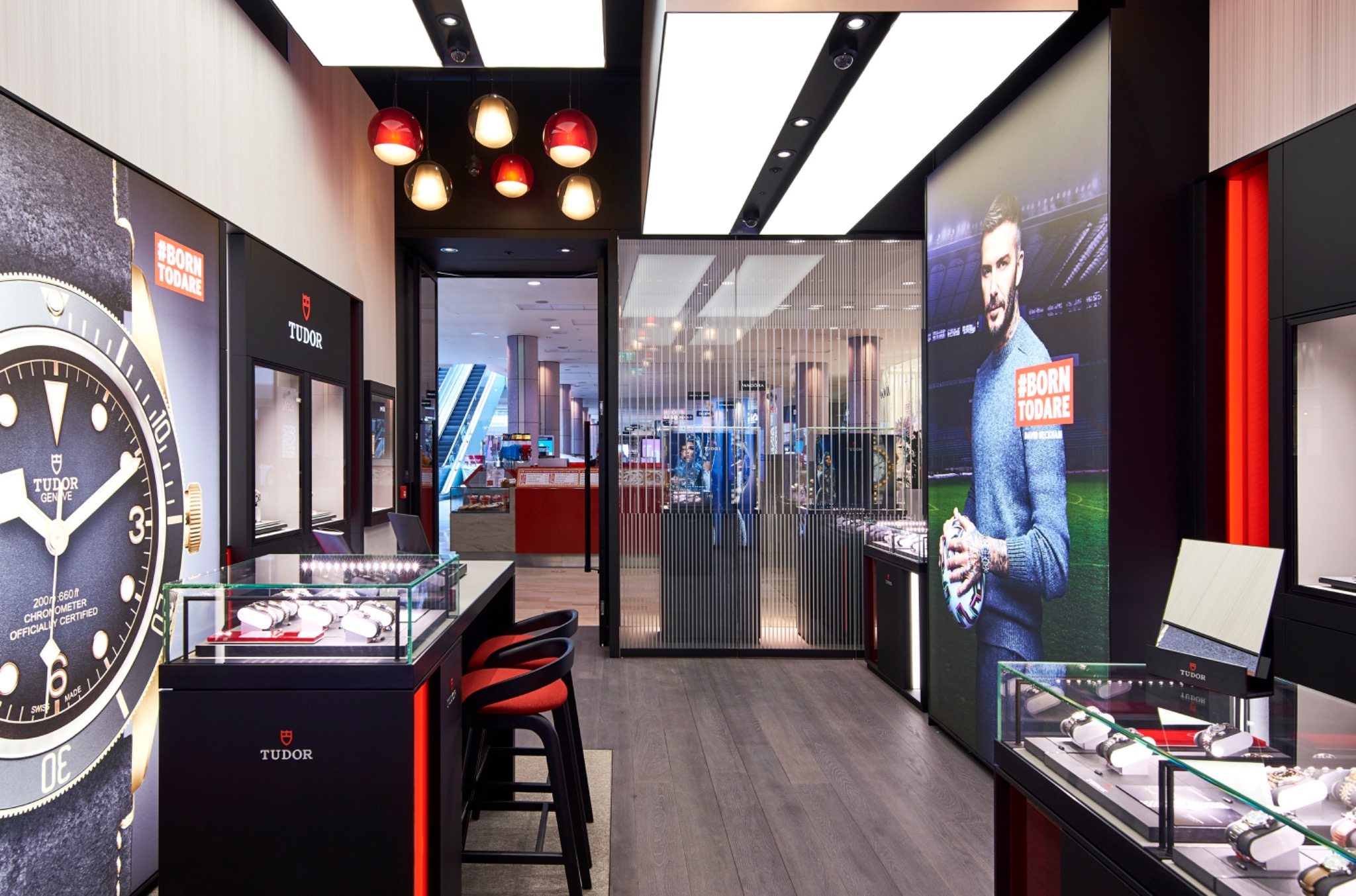 Tudor boutique interior with a prominent watch campaign image, illuminated cabinets and central display counter