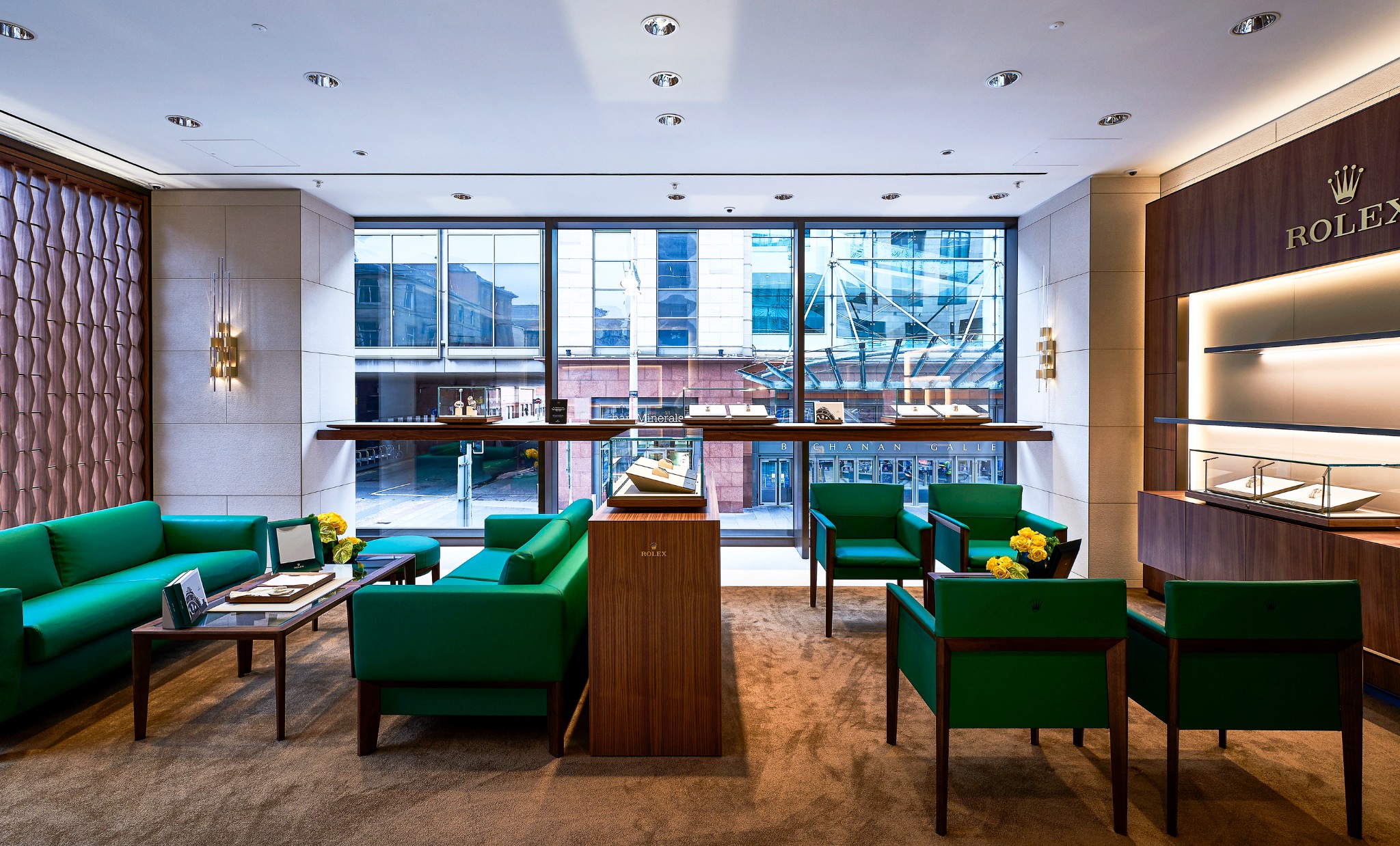 Lounge area within the Rolex Glasgow showroom, with green seating and a view towards the street