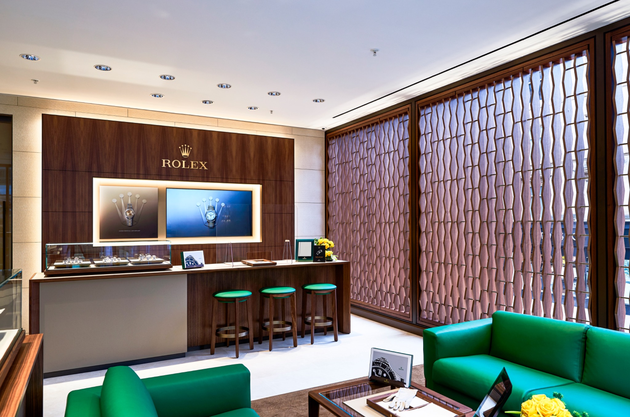 Textured screen, display counter and green seating within the Rolex Glasgow showroom