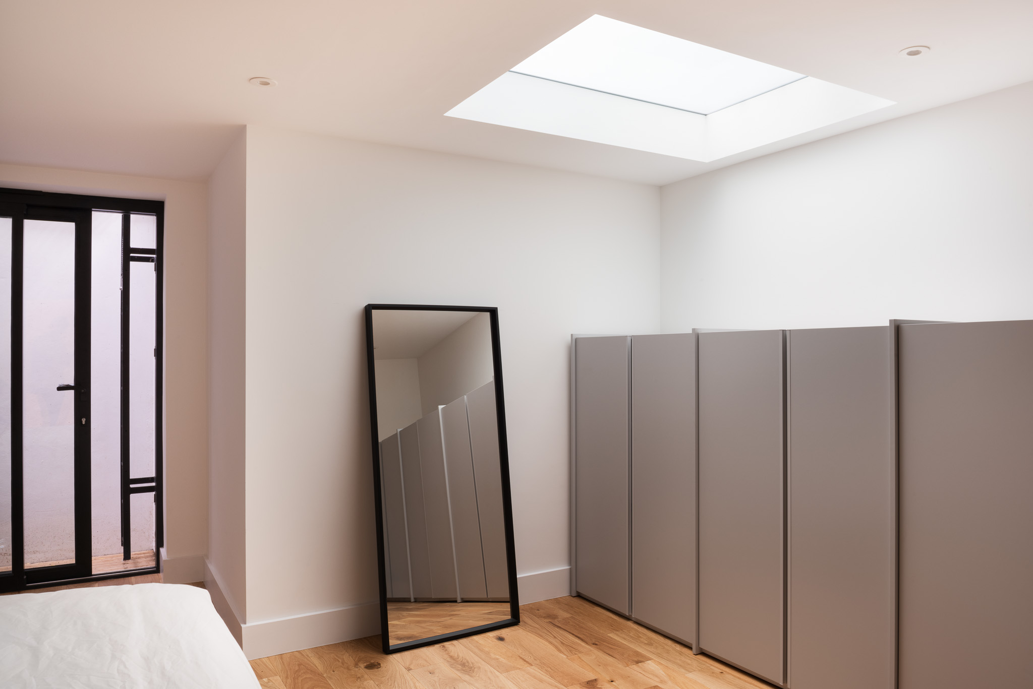 Bedroom with dark-framed doors, fitted wardrobes and a rooflight at Roupell Street, London
