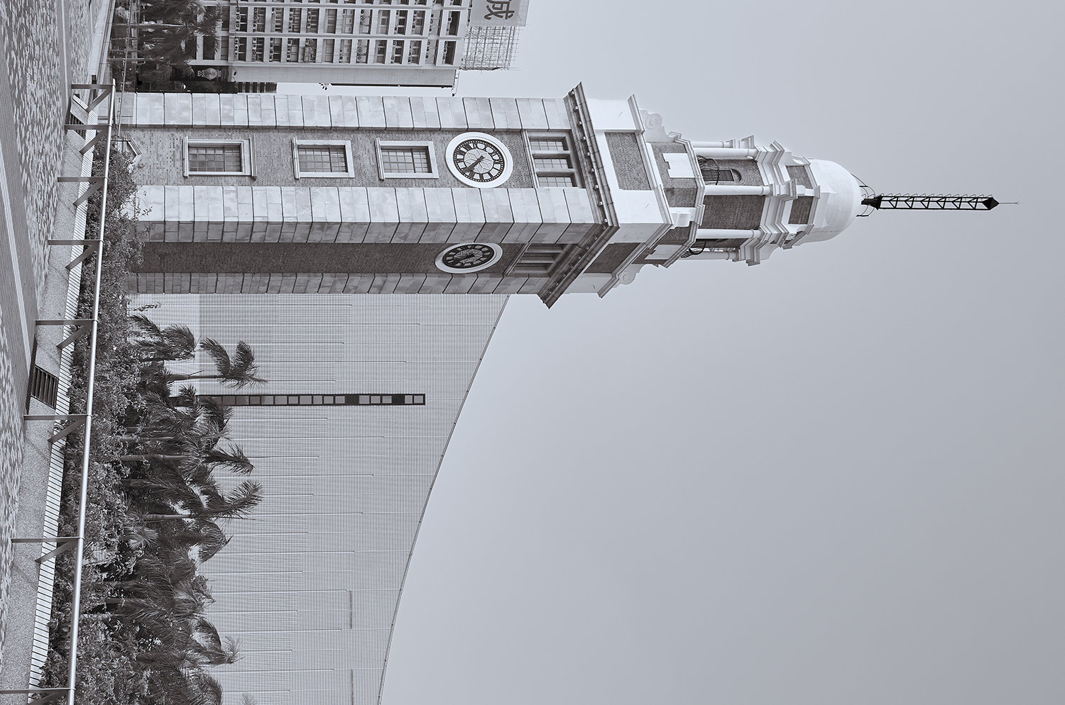 Kowloon–Canton Railway Clock Tower against the curved wall of the Hong Kong Cultural Centre