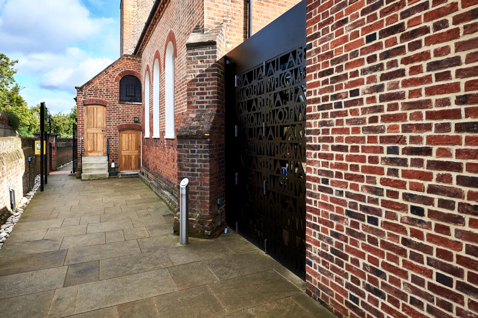 Narrow approach beside St Peter Church with the new brick extension and dark screen