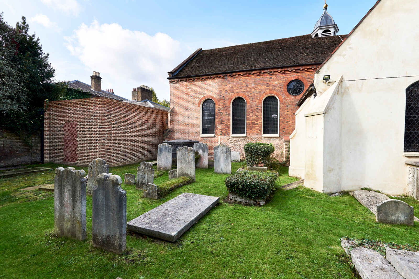 St Peter Church and its extension seen across gravestones and grass